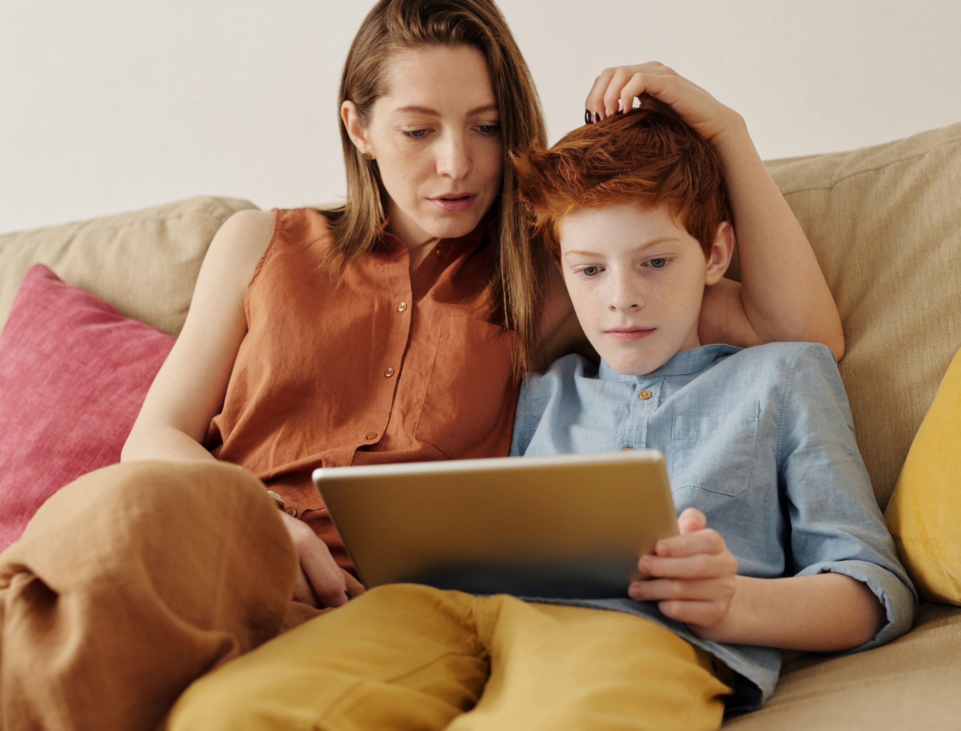 Parent and Son at home on the sofa, looking at an iPad together. Home-based Program Helps Families Find Calm in Child Behavior Modification
